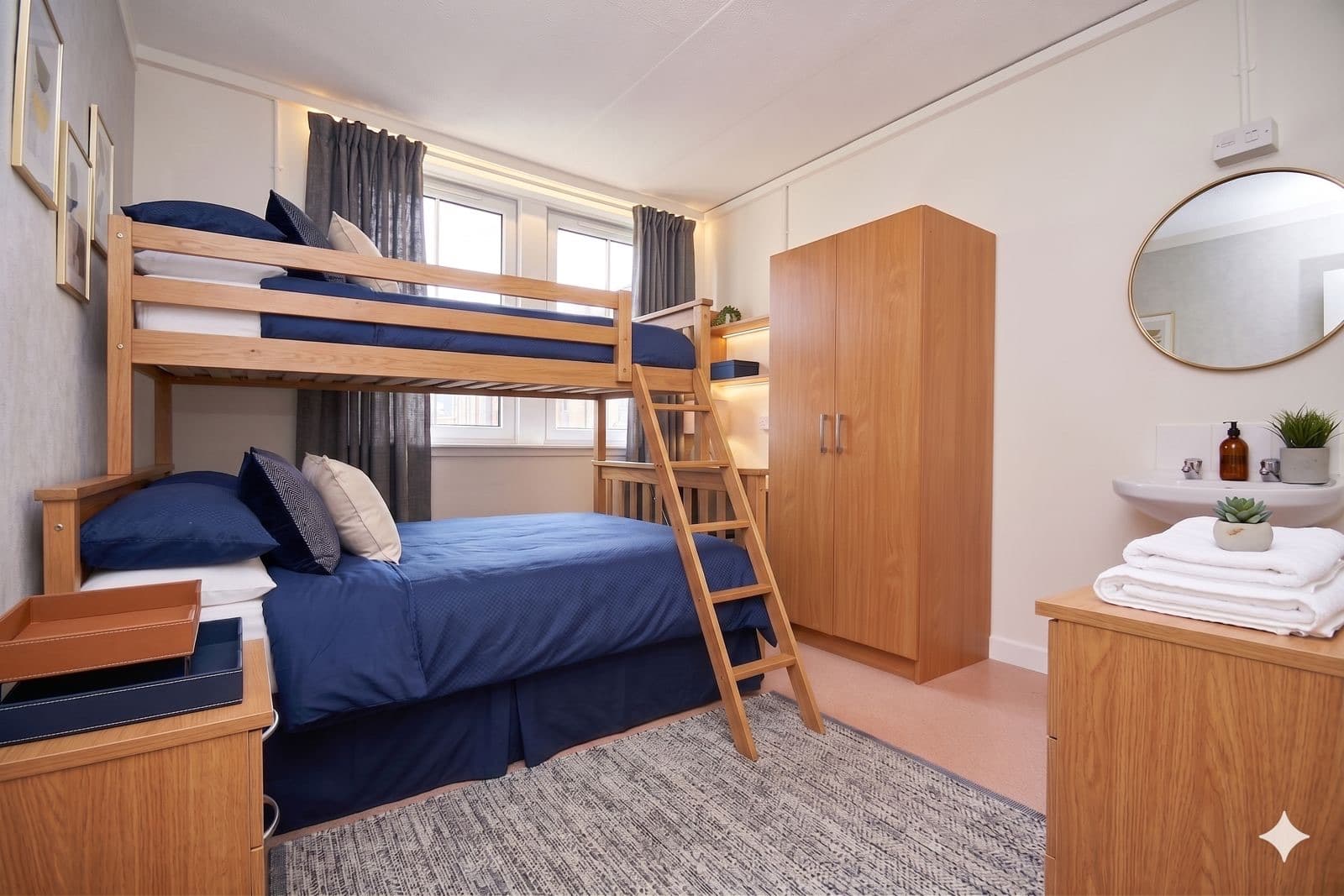 A private bunk room: a double bed below and a single bunk above, with a wardrobe and washbasin.