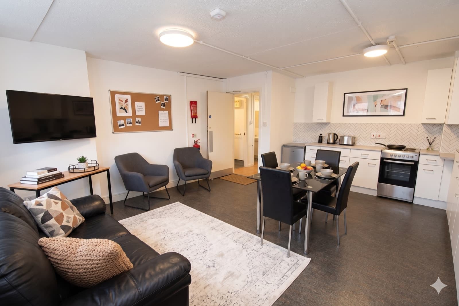 The shared kitchen and lounge, with a dining table, sofa, oven and television.
